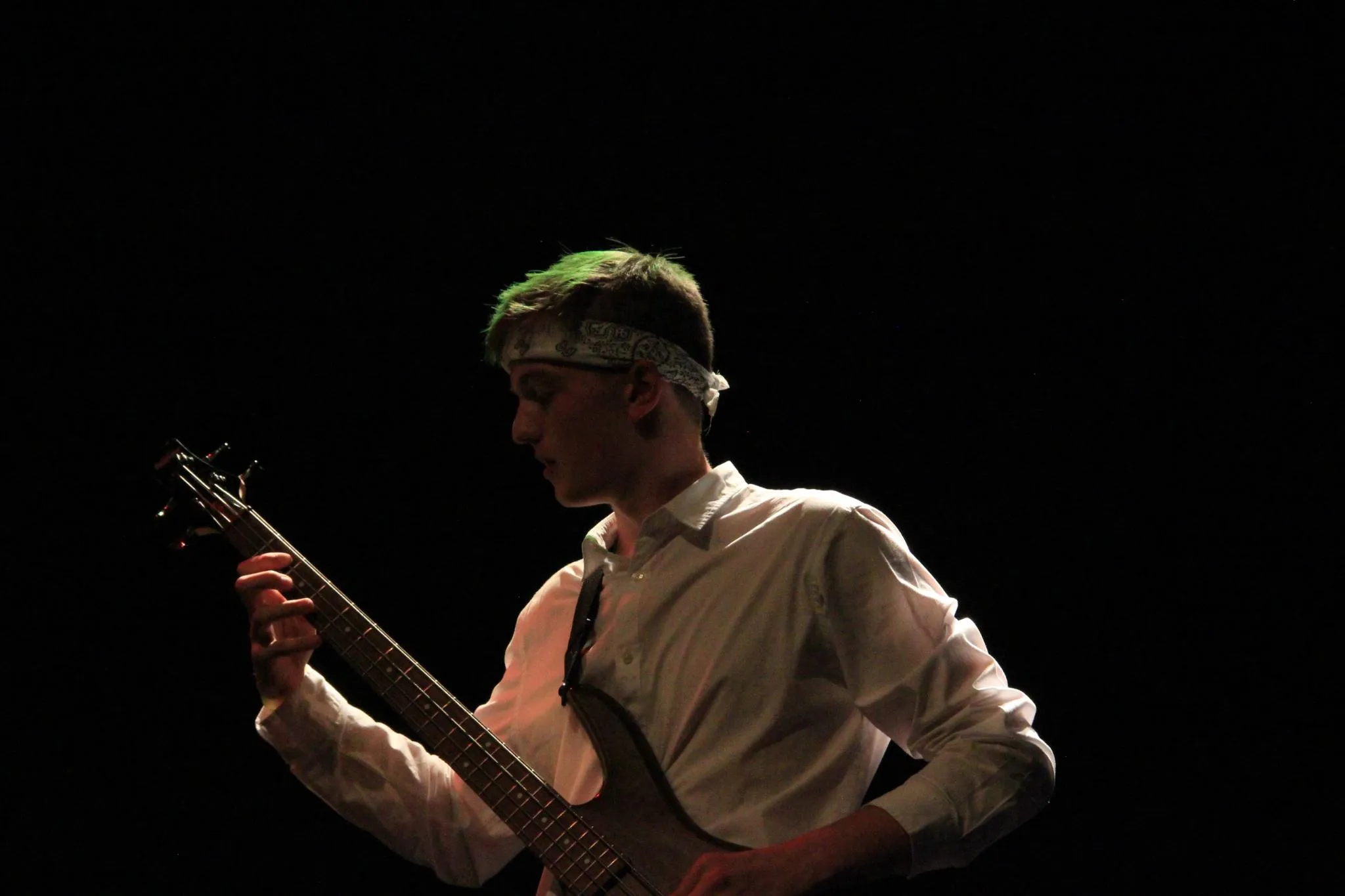 Nathan am E-Bass im Gegenlicht vor schwarzem Hintergrund